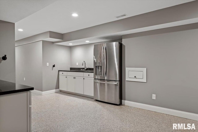 kitchen with white cabinetry, stainless steel fridge, and sink