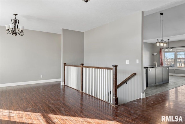 spare room with dark hardwood / wood-style flooring, a notable chandelier, and sink