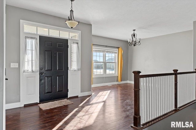 foyer entrance with an inviting chandelier and dark hardwood / wood-style floors