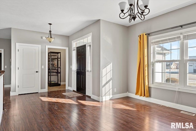 foyer entrance featuring dark wood-type flooring, a chandelier, and a wealth of natural light