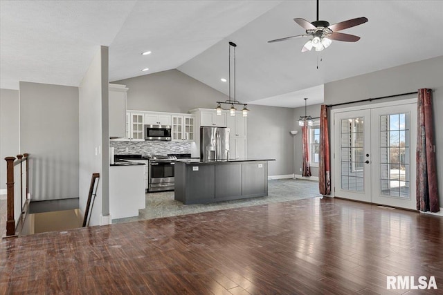 kitchen with appliances with stainless steel finishes, a kitchen island, white cabinets, pendant lighting, and backsplash