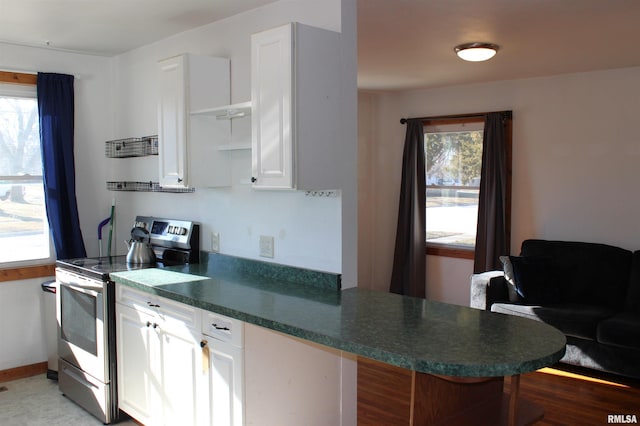 kitchen featuring electric stove, white cabinetry, kitchen peninsula, and a healthy amount of sunlight