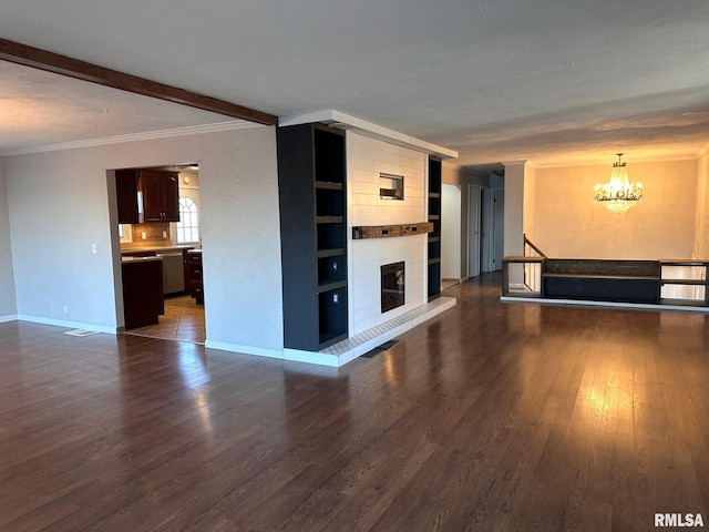 unfurnished living room with a notable chandelier, dark wood-type flooring, a fireplace, and built in shelves