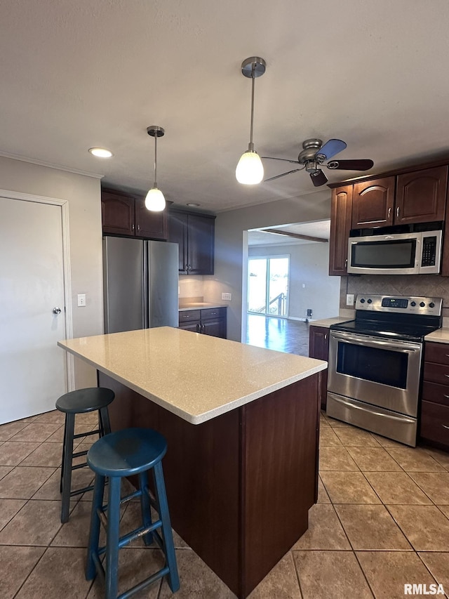 kitchen with stainless steel appliances, a center island, dark brown cabinets, and light tile patterned floors