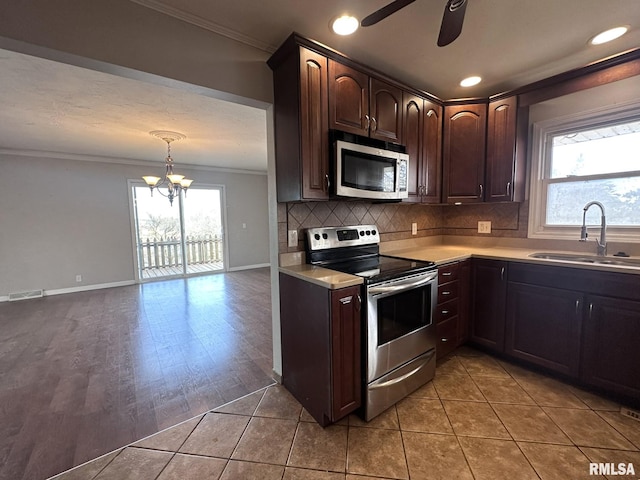 kitchen featuring sink, light tile patterned floors, dark brown cabinetry, stainless steel appliances, and crown molding