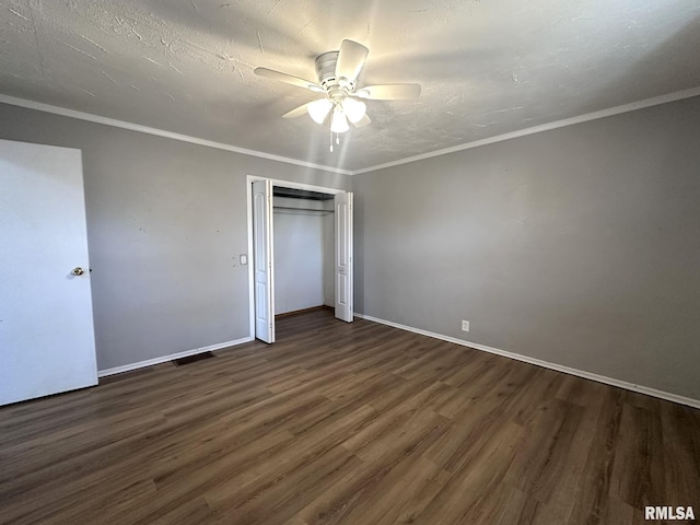 unfurnished bedroom with ornamental molding, dark wood-type flooring, ceiling fan, and a closet