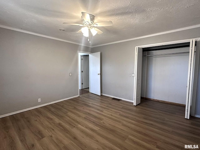 unfurnished bedroom with dark hardwood / wood-style flooring, crown molding, ceiling fan, and a closet