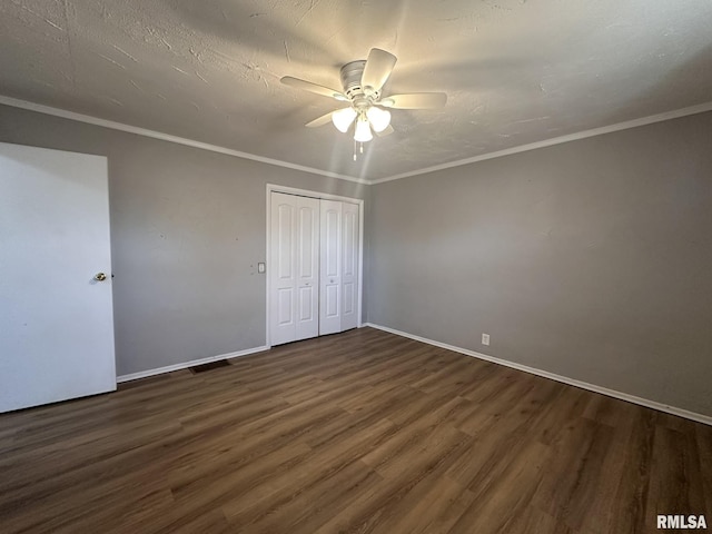 unfurnished bedroom featuring crown molding, dark hardwood / wood-style flooring, ceiling fan, and a closet