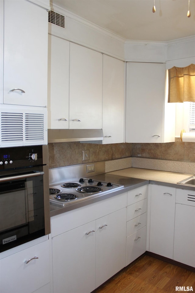 kitchen with stainless steel oven, cooktop, decorative backsplash, and white cabinets