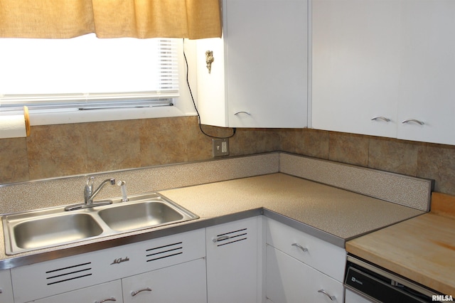 kitchen with white cabinetry, sink, and white dishwasher