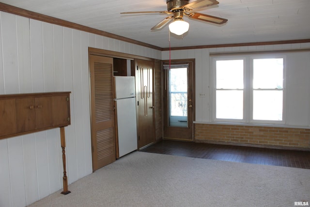 doorway to outside featuring crown molding, dark carpet, and wood walls