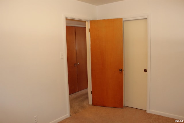 unfurnished bedroom featuring light colored carpet and a closet