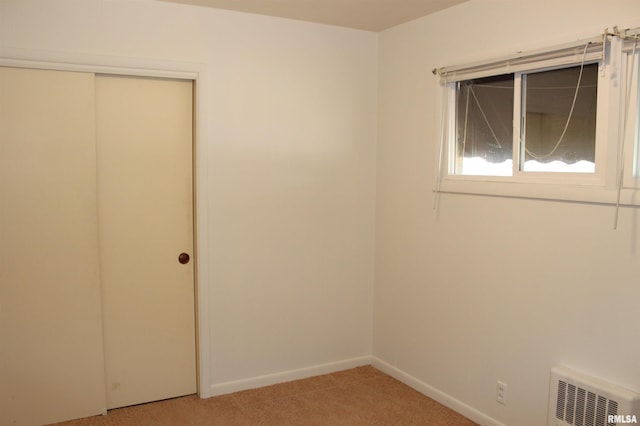 unfurnished bedroom featuring light carpet and a closet