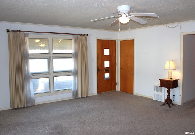 foyer with ceiling fan, ornamental molding, carpet floors, and a textured ceiling