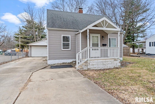 bungalow with an outbuilding, a garage, a front yard, and a porch