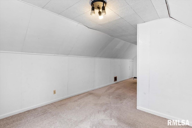 bonus room with light colored carpet and vaulted ceiling