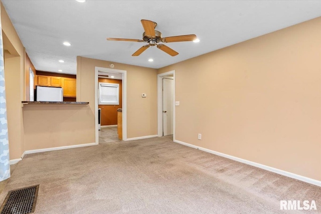 unfurnished living room featuring light colored carpet and ceiling fan