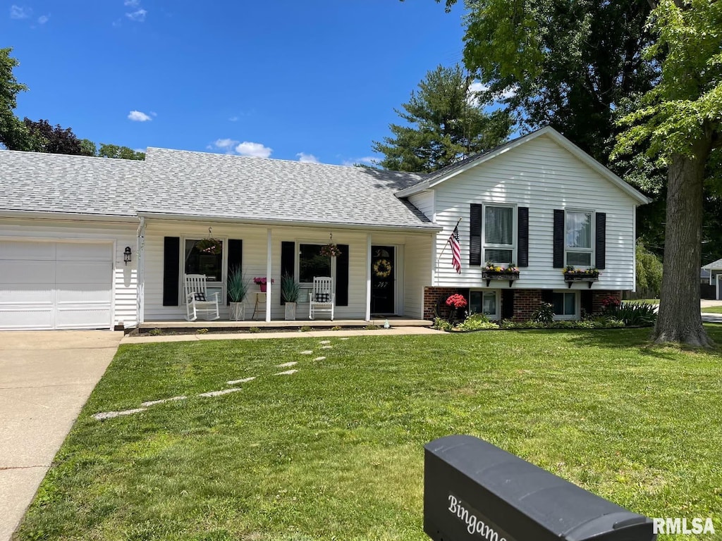 split level home with covered porch, a garage, a shingled roof, concrete driveway, and a front yard