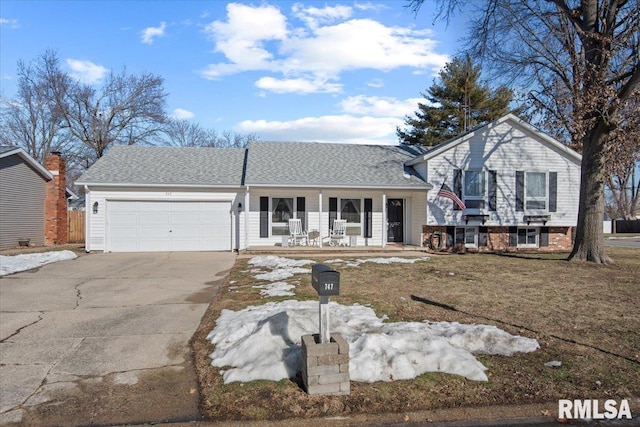 split level home featuring a garage, covered porch, and a front yard