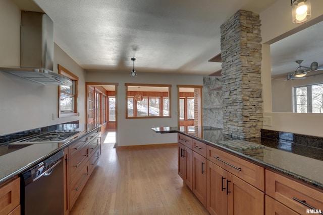 kitchen featuring a healthy amount of sunlight, wall chimney exhaust hood, dishwasher, and dark stone countertops