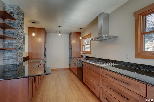 kitchen featuring pendant lighting, stainless steel gas stovetop, dishwashing machine, and wall chimney range hood