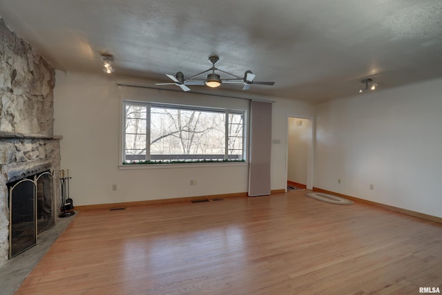 unfurnished living room featuring ceiling fan, a fireplace, and light hardwood / wood-style flooring