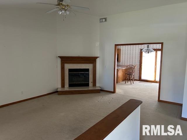 unfurnished living room featuring ceiling fan with notable chandelier and light carpet