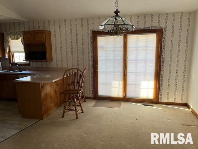 unfurnished dining area featuring carpet floors, sink, and a notable chandelier