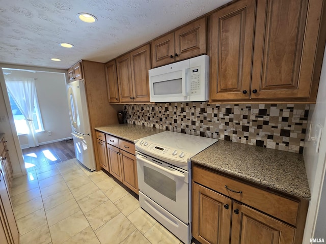 kitchen with white appliances, light tile patterned floors, a textured ceiling, and backsplash