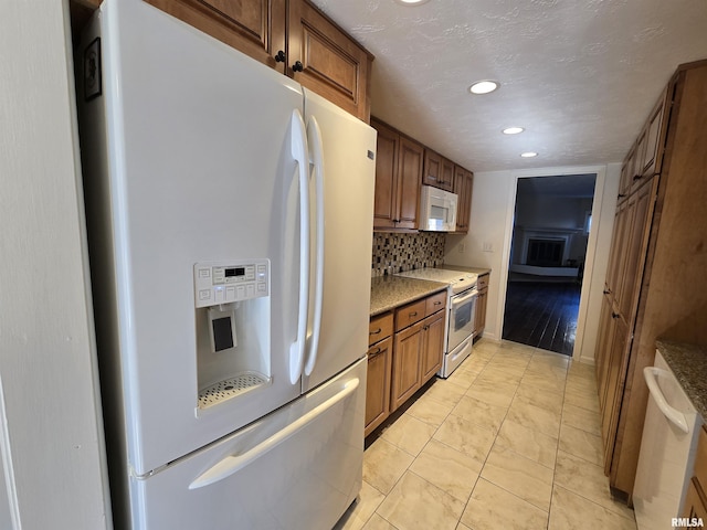 kitchen featuring white appliances, stone countertops, light tile patterned floors, and backsplash