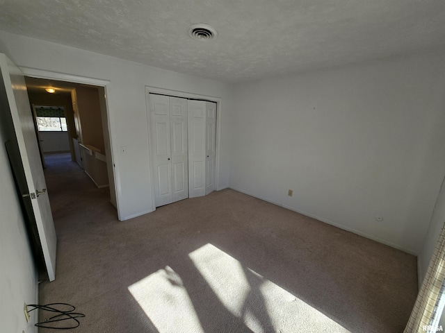 unfurnished bedroom featuring carpet, a textured ceiling, and a closet