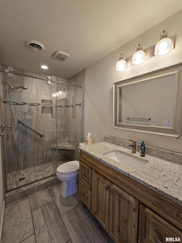 bathroom featuring vanity, a shower with door, and toilet