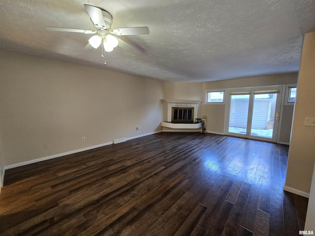 unfurnished living room featuring ceiling fan, a textured ceiling, and dark hardwood / wood-style flooring