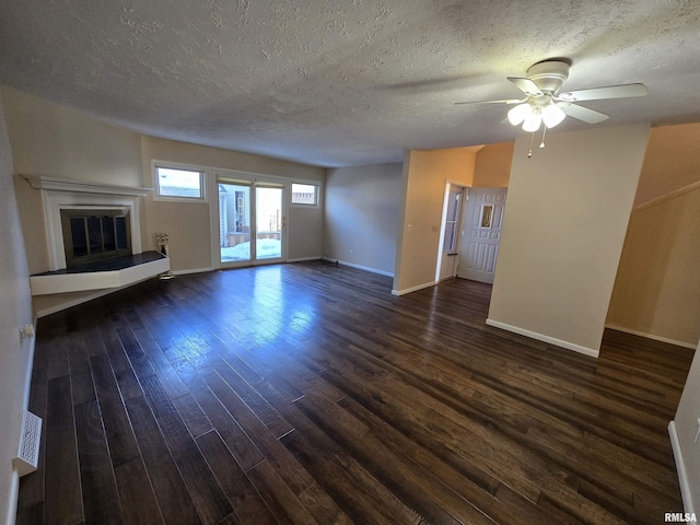 unfurnished living room with ceiling fan, dark hardwood / wood-style flooring, and a textured ceiling