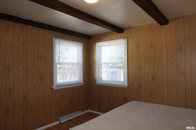 unfurnished bedroom featuring beam ceiling, a baseboard radiator, and wood walls