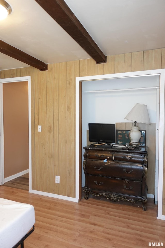 bedroom featuring wood-type flooring, beam ceiling, and wood walls