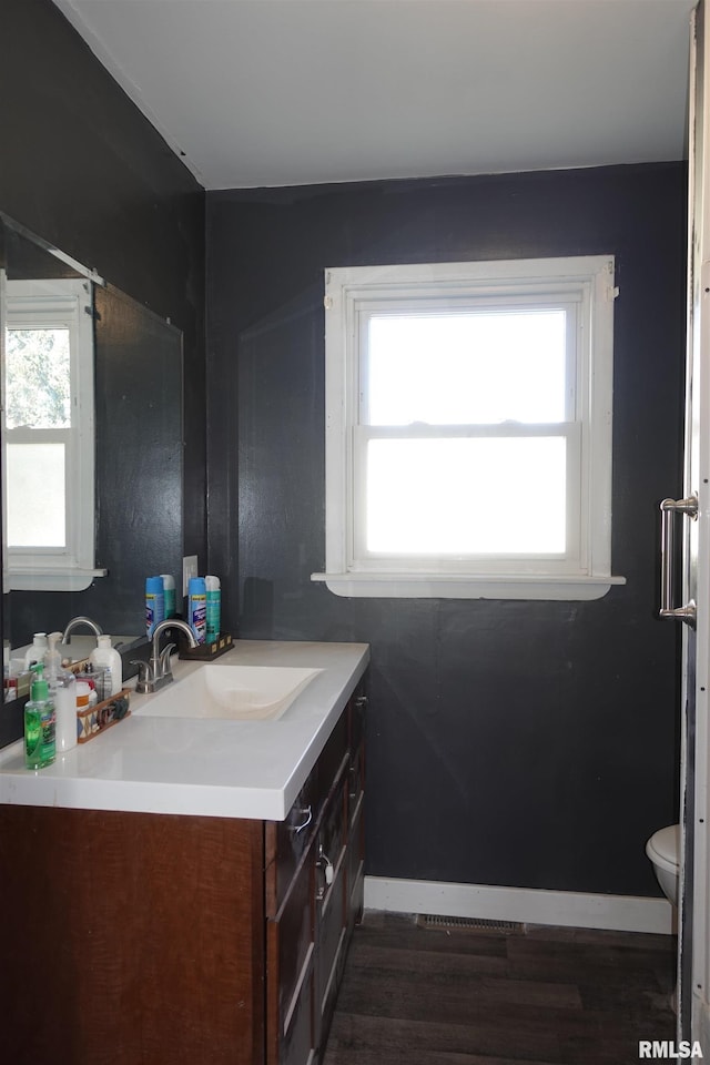 bathroom with a healthy amount of sunlight, vanity, hardwood / wood-style floors, and toilet