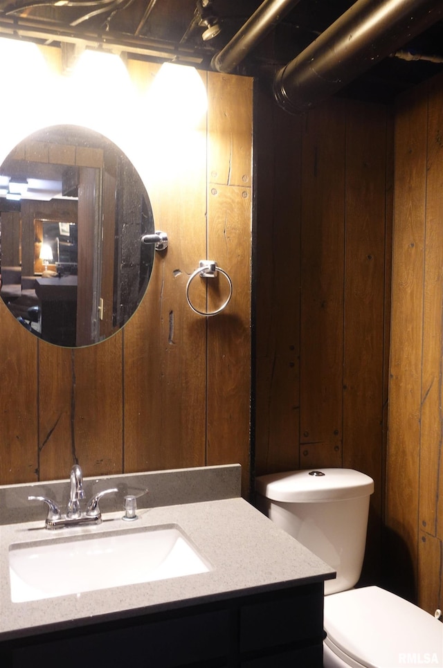 bathroom featuring vanity, toilet, and wood walls