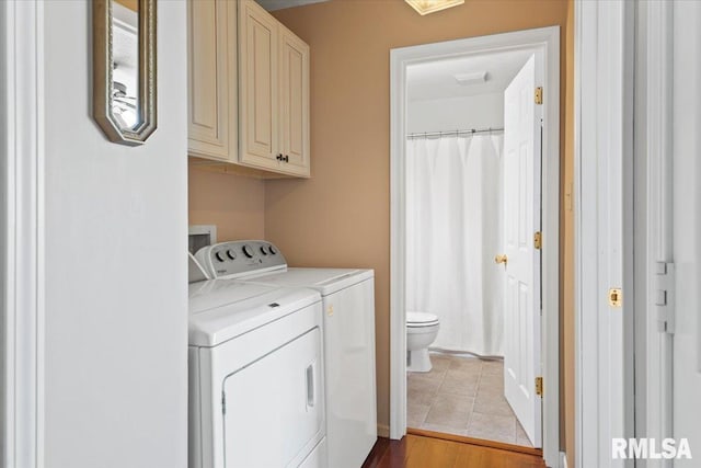 washroom featuring separate washer and dryer, light hardwood / wood-style flooring, and cabinets