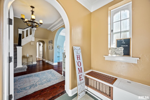 foyer entrance featuring ornamental molding, an inviting chandelier, and dark hardwood / wood-style flooring