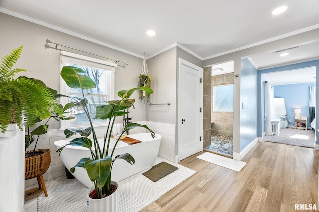 doorway with crown molding, light hardwood / wood-style flooring, and tile walls