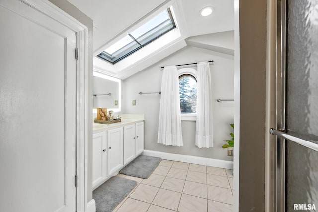 bathroom featuring lofted ceiling with skylight, vanity, and tile patterned floors