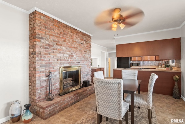 dining area featuring crown molding, ceiling fan, and a brick fireplace