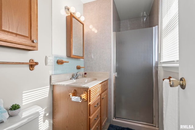 bathroom featuring vanity, toilet, decorative backsplash, and a shower with shower door