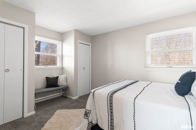 bedroom featuring dark colored carpet and two closets