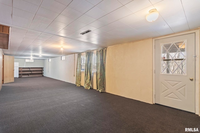 basement featuring dark carpet and white fridge