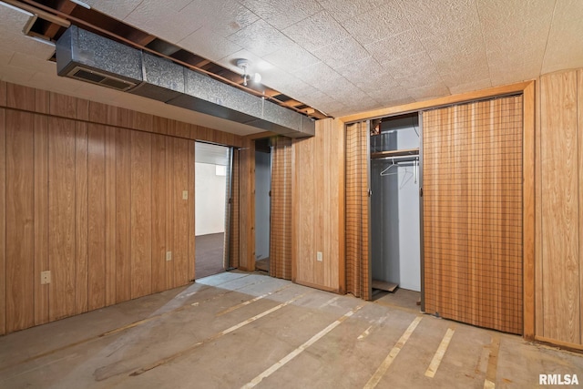 unfurnished bedroom featuring wooden walls and a closet