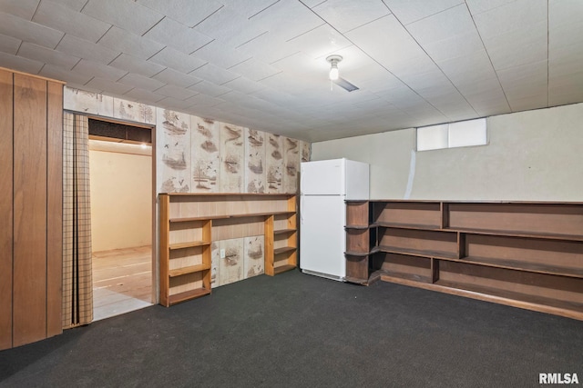 basement featuring dark carpet and white refrigerator