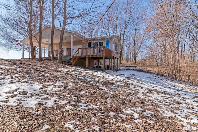 snow covered back of property with a deck