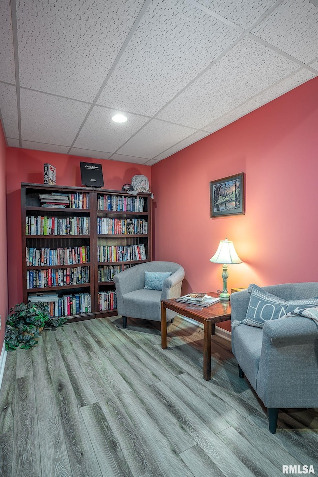 living area featuring a paneled ceiling and hardwood / wood-style floors